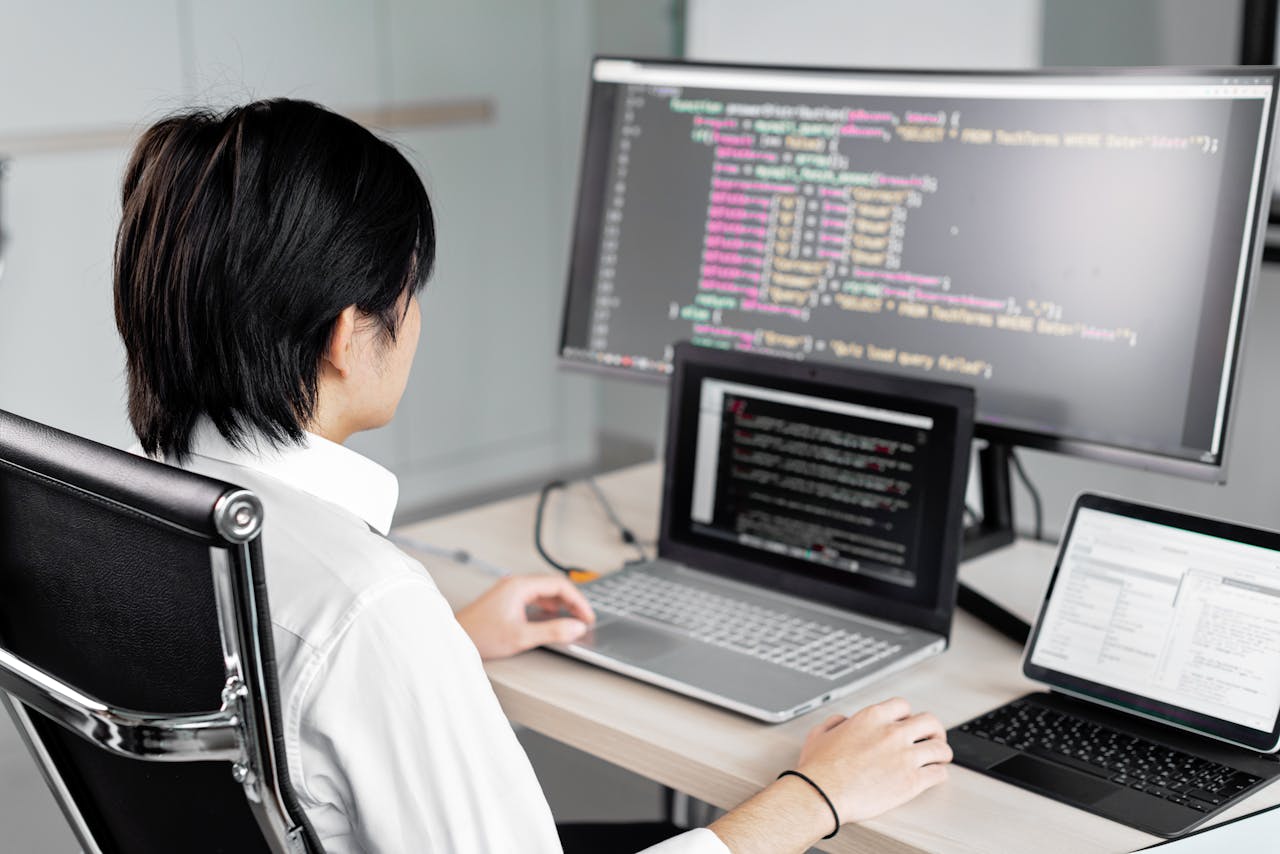 why-choose-us A software developer working on code with multiple screens in a modern office setting.